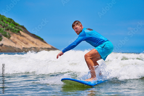 Sticker young caucasian man on a small wave learning to surf in the atlantic ocean