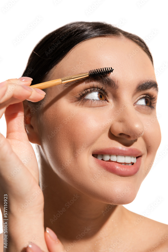 close up of happy young woman styling eyebrows with brush and gel isolated on white. close up of happy young woman styling eyebrows with brush and gel isolated on white.