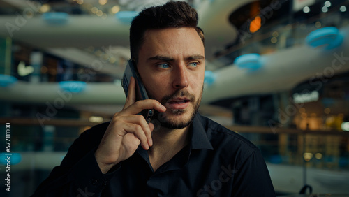 Caucasian hispanic male consultant businessman young man employee speak mobile phone in business company talk mobile phone remote call negotiate cell conversation use telephone smartphone communicate