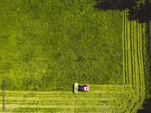 Top down view of a tractor mowing a grass field in straight lines all around