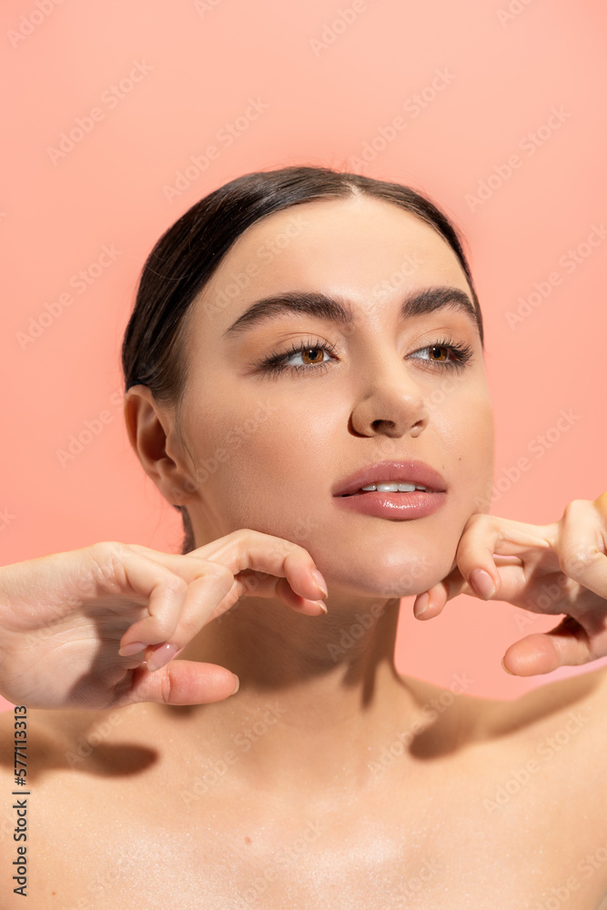 brunette young woman with soft skin doing face massage isolated on pink. brunette young woman with soft skin doing face massage isolated on pink.