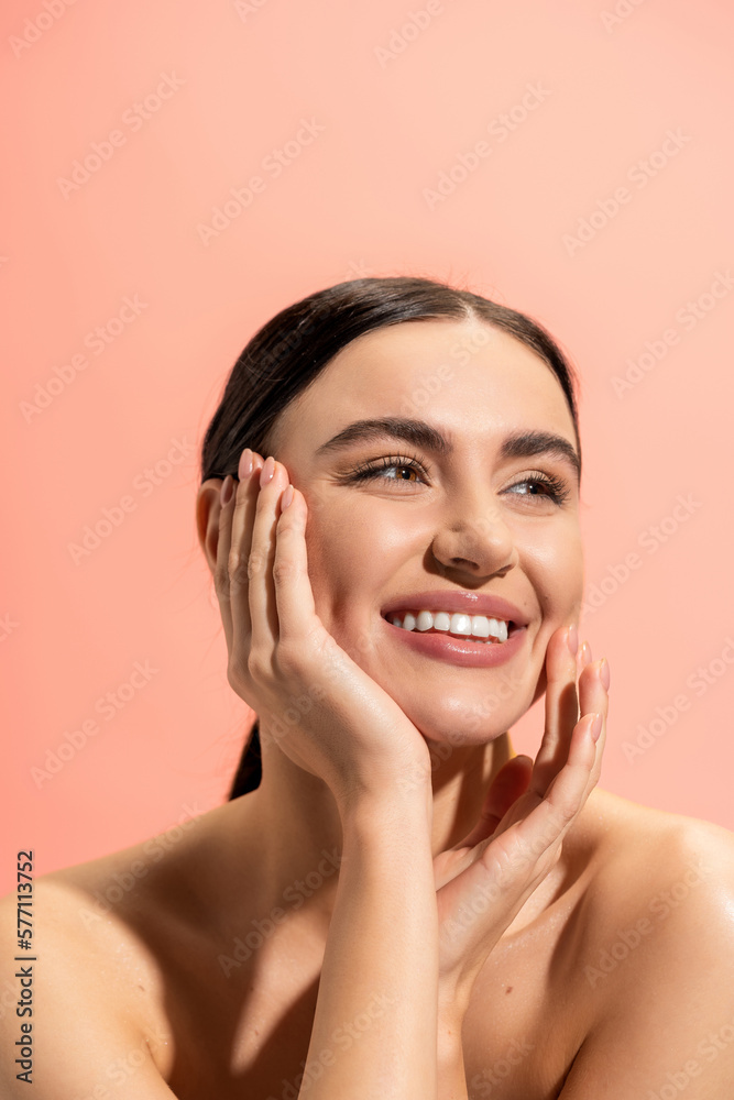 smiling woman with bare shoulders looking away while touching cheek isolated on pink. smiling woman with bare shoulders looking away while touching cheek isolated on pink.