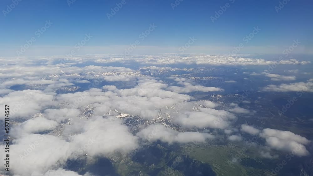 Aerial view of ground and mountain. Flight high through moving clouds on the sky. Looking of horizon out the window airplane seeing wonderful landscape and earth. Travel and transportation concept. Aerial view of ground and mountain. Flight high through moving clouds on the sky. Looking of horizon out the window airplane seeing wonderful landscape and earth. Travel and transportation concept.