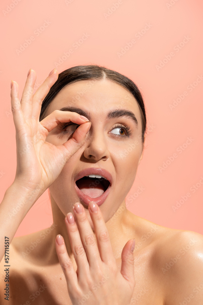 amazed woman covering opened mouth and showing ok sign isolated on pink. amazed woman covering opened mouth and showing ok sign isolated on pink.