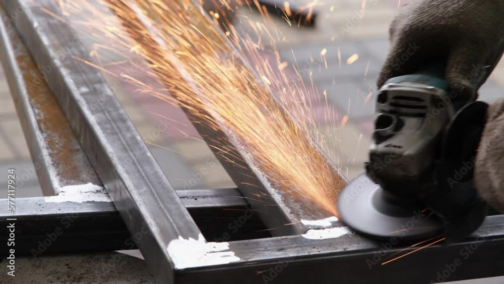 A man working with electric grinder tool on Steel beam. sparks flying. Electric grinding. Remove rust