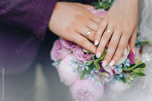 hands with wedding rings. hands of the bride and groom with wedding rings and bridal bouquet. the groom gently holds the bride's hand © Maksym