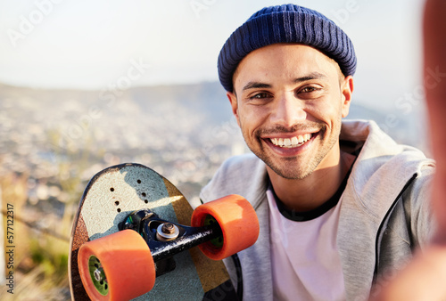 Portrait, selfie and view with a skater man in nature, taking a picture while outdoor for a skate. Summer, skateboard or photograph with a happy male outside in the mountains for recreation skating photo