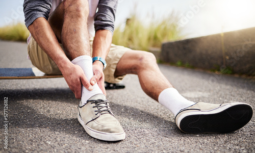 Fitness, athlete and man with ankle injury, pain or accident while skateboarding in the street. Sports, exercise and male skateboarder with muscle sprain, medical emergency or injured leg in the road