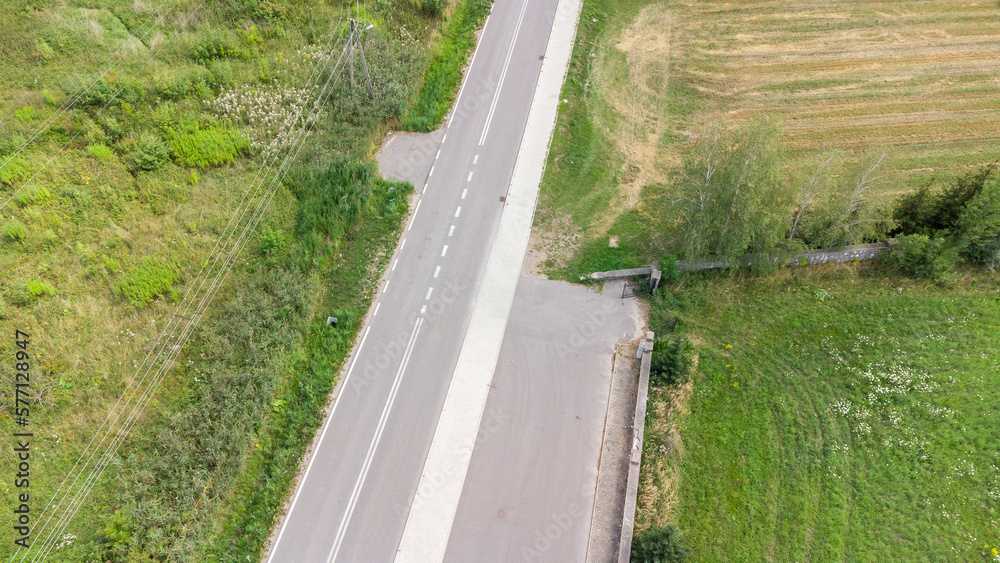 Simple empty two lane road, countryside rural area drone view, aerial shot, nobody, no cars, no people, power lines. Eastern Europe, small European road seen from above, copy space background, fields