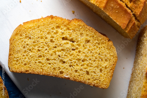 Beautiful homemade yellow, sliced cornbread loaf. Freshly baked cornbread on wooden background.