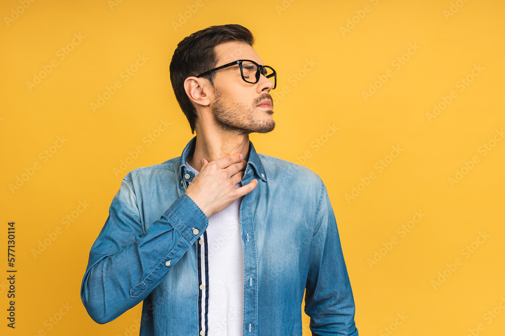 Fototapeta premium Sore throat. Young bearded men touching the neck isolated against yellow background. Virus cold and flu concept.