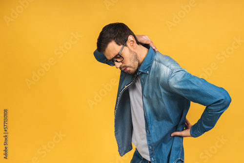 Young handsome man wearing casual standing over isolated yellow background. Suffering of backache, touching back with hand, muscular pain. © denis_vermenko