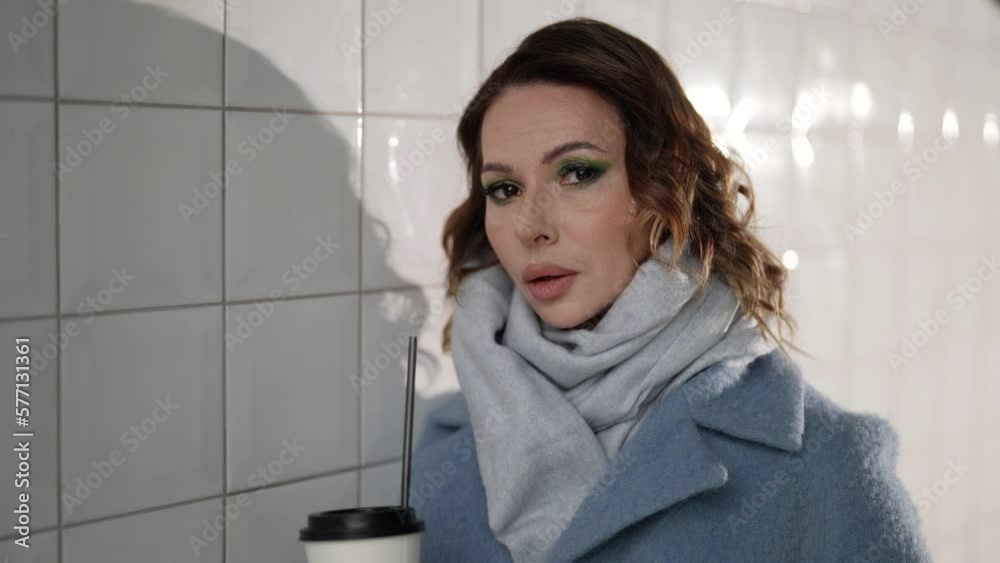 pensive and melancholic woman in light blue coat, looking at camera by her dark eyes, portrait pensive and melancholic woman in light blue coat, looking at camera by her dark eyes, portrait