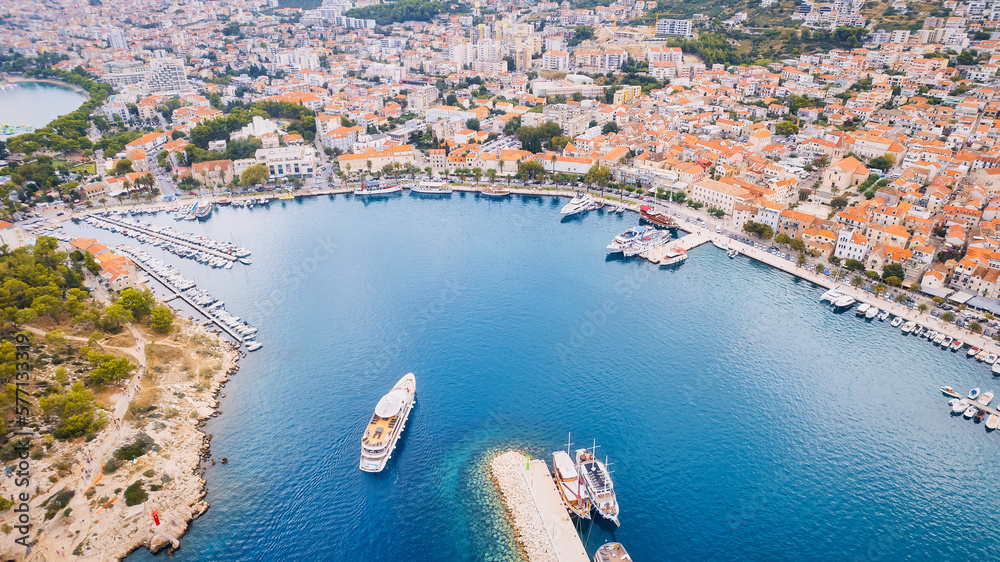 Croatia's harbor is a sight to behold from above. This breathtaking aerial view captures the colorful landscape filled with sailboats, motorboats, and luxurious yachts resting in a clear blue bay. Add - obrazy, fototapety, plakaty 