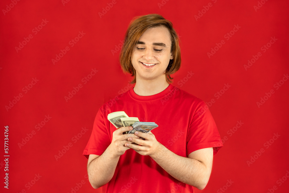 Emotional young man with cash. Guy with currency banknotes. The concept of a successful money story, start-up, student loan, part-time job, winning Emotional young man with cash. Guy with currency banknotes. The concept of a successful money story, start-up, student loan, part-time job, winning