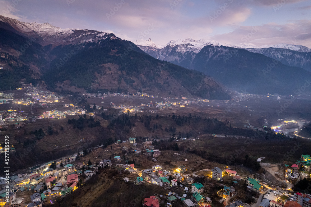 aerial drone shot of manali hill station blue hour evening with building lights at dusk showing valley with fog covered himalaya mountains showing tourist spot in himachal