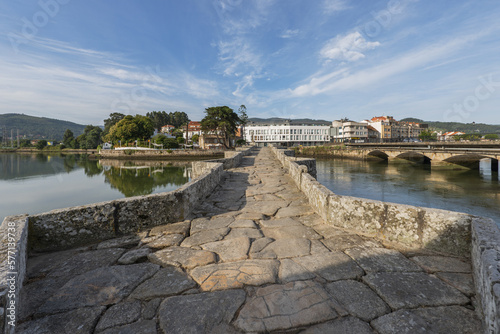 View over the Romanesque bridge that crosses the Miñor river in La Ramallosa that connects Baiona with Nigran in Galicia, Spain a beautiful summer morning with the calm water photo