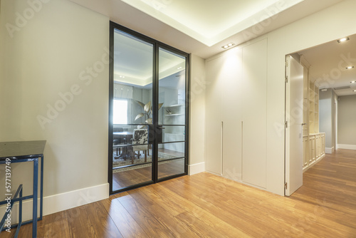 distributor of a house with access to several rooms with built-in wardrobes  custom-made wooden bookcases and black metal and glass doors