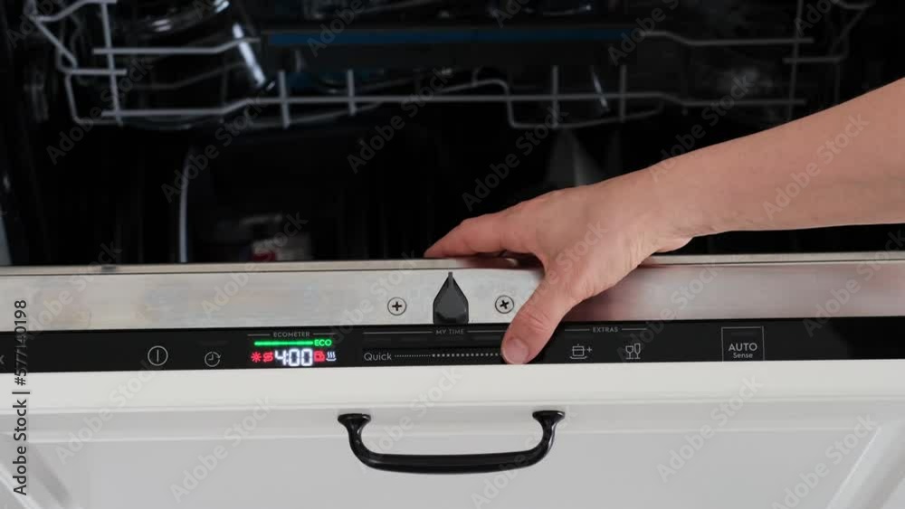 A woman hand is choosing a dishwashing program on a builtin dishwasher