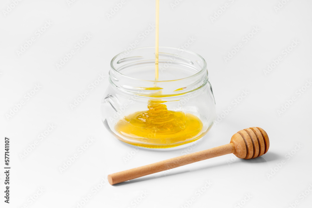 Honey is poured into an empty jar on a white background. Honey is poured into an empty jar on a white background.