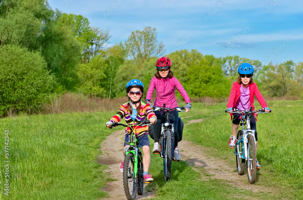 Happy mother and kids on bikes cycling outdoors in park, active family sport  and fitness together
