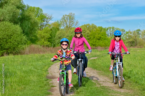 Happy mother and kids on bikes cycling outdoors in park, active family sport and fitness together 