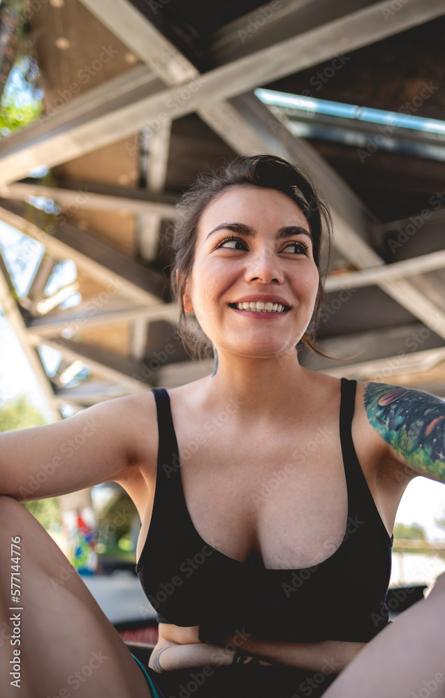 Rebel style: portrait of happy and sexy young woman with black top and short, tattoos and skateboard in urban skate park under a bridge Rebel style: portrait of happy and sexy young woman with black top and short, tattoos and skateboard in urban skate park under a bridge