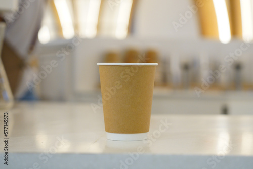 Mock-up on a white coffee shop background. Mock-up of a brown paper cup in the morning.             