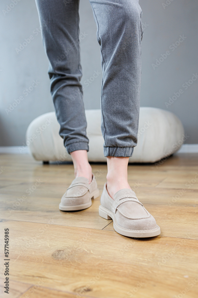Female legs close-up in gray shoes without heels. Women's comfortable summer casual shoes. Gray women's spring shoes Female legs close-up in gray shoes without heels. Women's comfortable summer casual shoes. Gray women's spring shoes