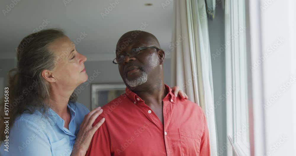 Happy senior diverse couple wearing shirts and embracing in living room Happy senior diverse couple wearing shirts and embracing in living room