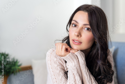 Portrait of a lovely woman resting in an armchair. A delightful brunette looks into the camera.