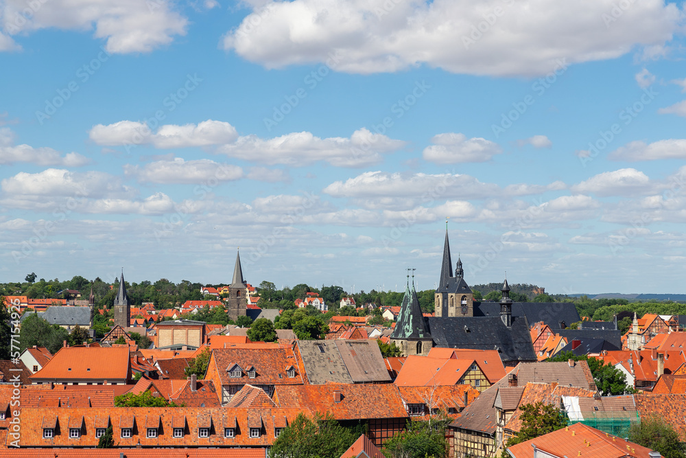 Scenic panoramic view traditional shingle tiled red rooftop old ancient medieval european german small town Quedlinburg church against blue sky background. Unesco heritage list travel destination