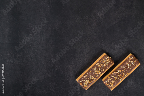 Two Crispy cookies in the form of strips glazed with chocolate, with nuts and cereals. Dark gray background. Top view. Copy space