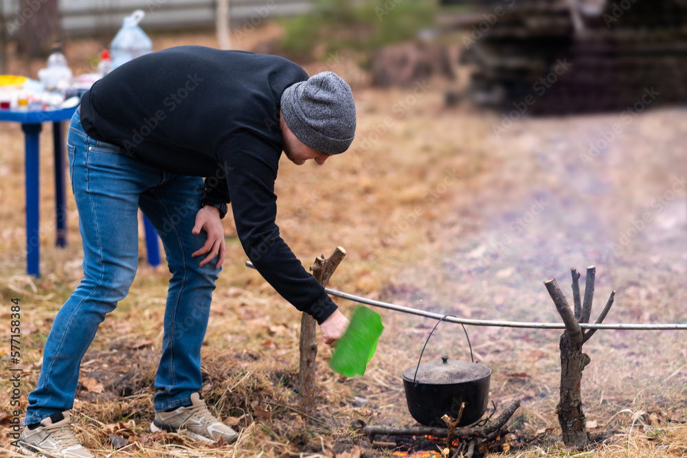 Young man fanning fire for cooking