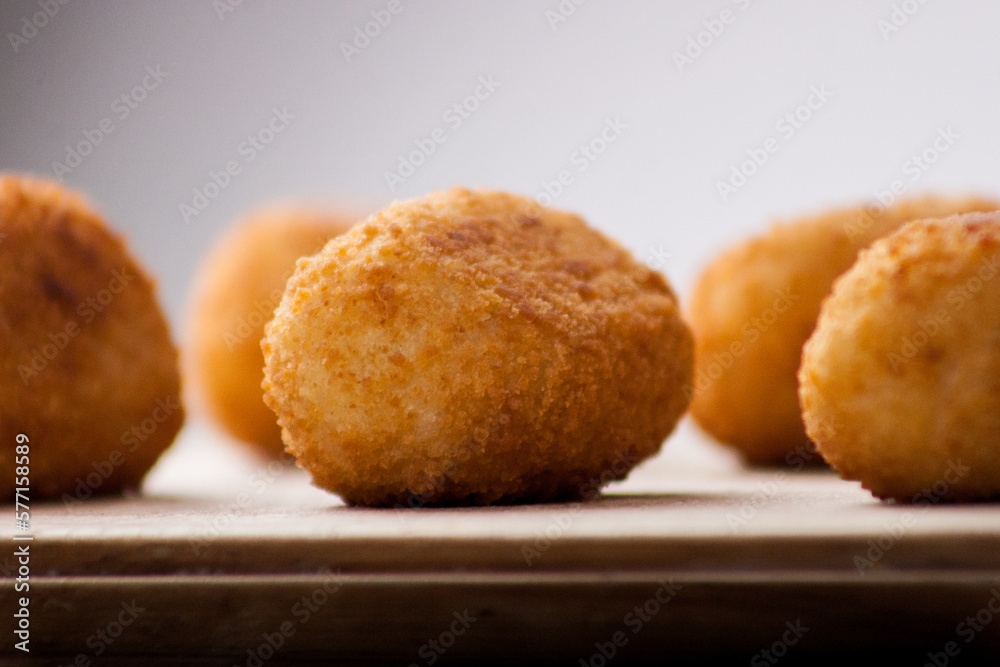 Classic Spanish croquettes on wooden board with dim light in the background	
