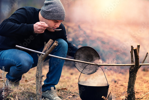 Obraz na płótnie Young man at sunset preparing food on a campfire w salonie
