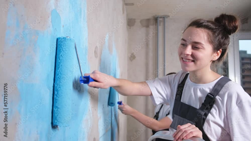 Couple in new home during repair works painting wall together. Happy