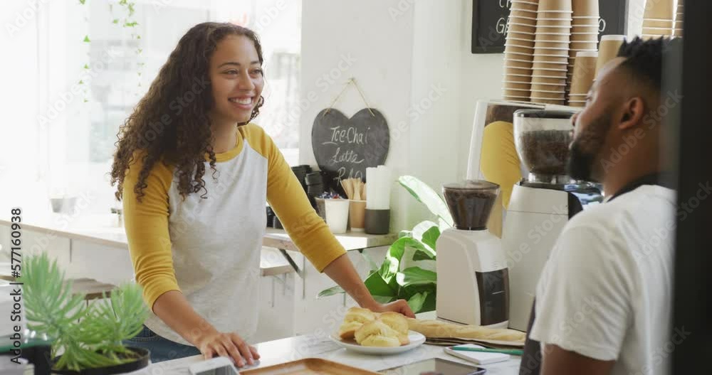 Happy african american male barista taking order from biracial female client at cafe Happy african american male barista taking order from biracial female client at cafe
