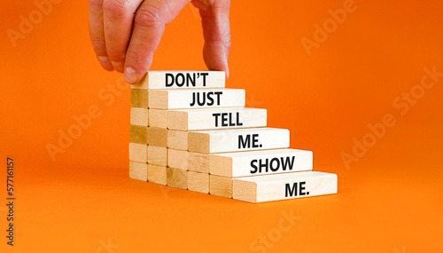 Tell or show symbol. Concept words Do not just tell me, show me on wooden blocks. Beautiful orange table orange background. Businessman hand. Business tell or show concept. Copy space.