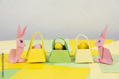 Two pink paper Easter bunnies, origami crafts and egg baskets, place for text