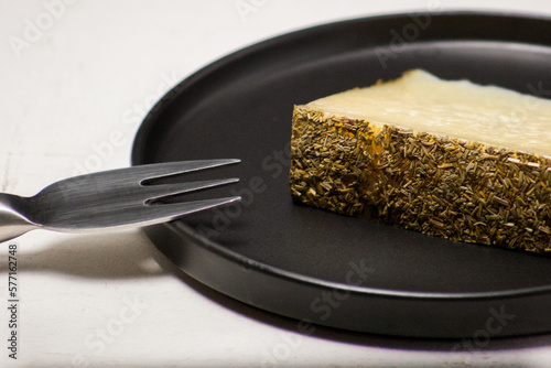 Truffle cheese on a black plate with a silver-plated topping