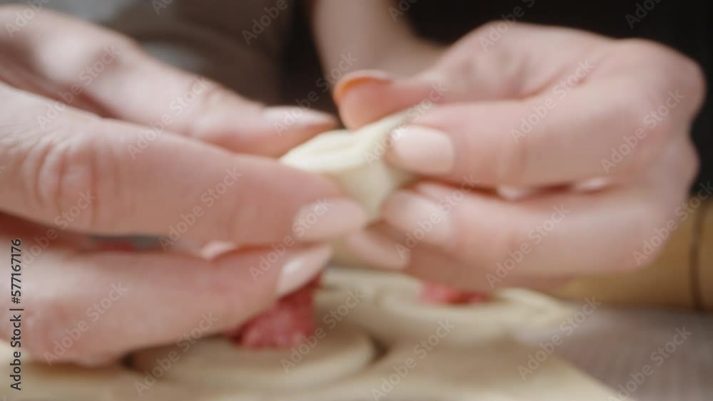 The girl takes a round piece of dough, on which there is minced meat, and wraps it. Homemade dumplings, close-up. Wide angle. The girl takes a round piece of dough, on which there is minced meat, and wraps it. Homemade dumplings, close-up. Wide angle.