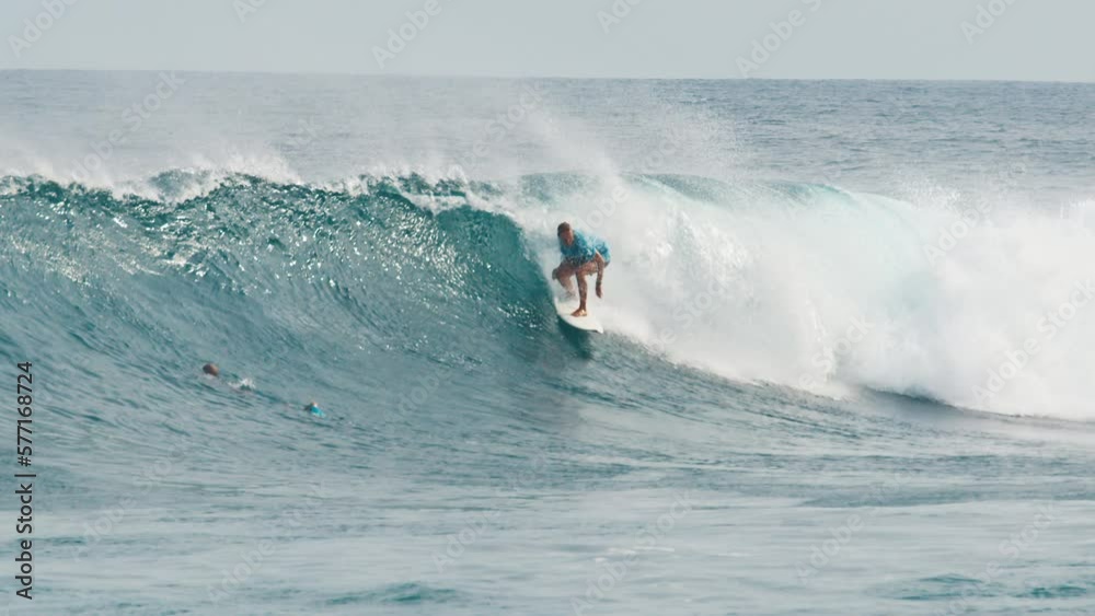 Surfer surfs the wave. Male surfer rides the wave in the Maldives Surfer surfs the wave. Male surfer rides the wave in the Maldives