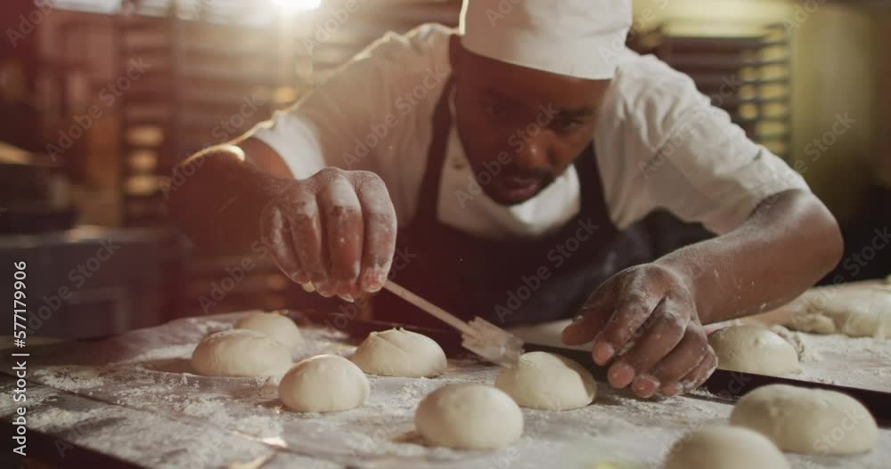 Animation of focused african american male baker preparing rolls