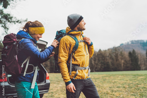 Couple of hikers helping each other get ready before going on a hike 