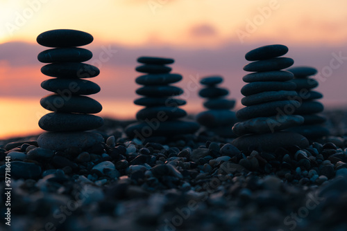 Balanced pebble pyramid silhouette on the beach on sunset with Sea on the background. Zen stones on the sea beach  meditation  spa  harmony  calmness  balance concept.