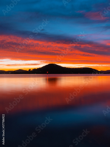 Dramatic red clouds over lake and mountains at dawn.