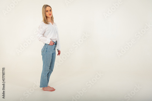 Portrait of a young, emotional, happy girl without makeup, smiling at the camera, gesturing with her hands, standing on a white background. Place for writing 