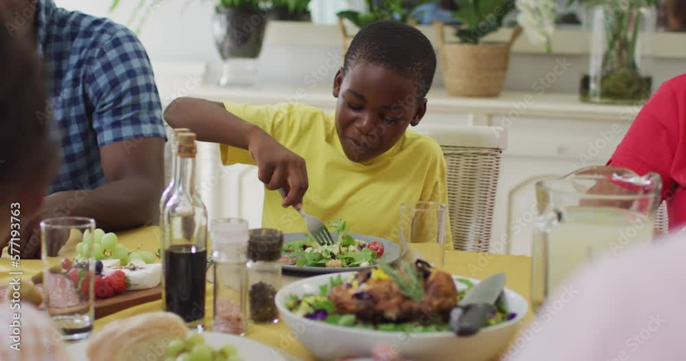 Happy african american boy eating lunch with family at home Happy african american boy eating lunch with family at home