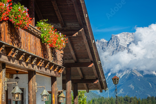 Obraz na płótnie Alpine Chalet with flowers at springtime and Zugspitze mountain, Bavarian Alps w salonie